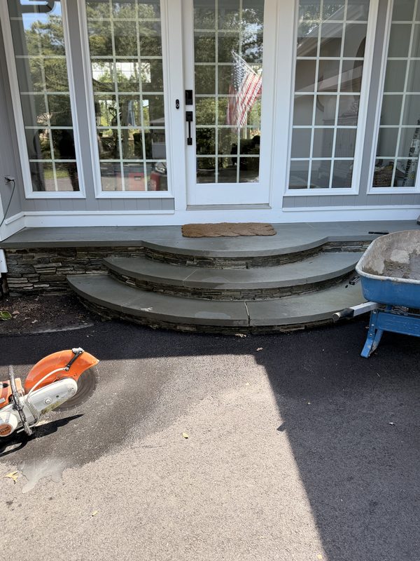 Curved bluestone entry steps on stacked ledgestone risers, set at a pair of French doors