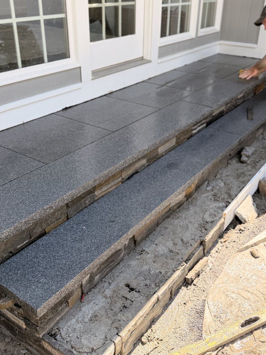 After — thermal-finish granite, full slabs two risers deep, run out to a landing that reaches the sill