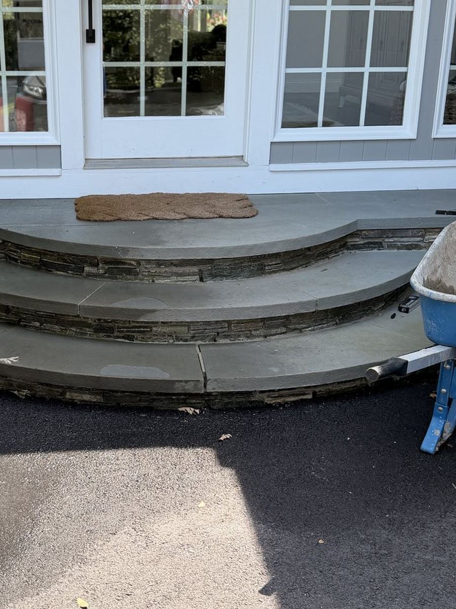Before — the curved bluestone flight on a thin stone skirt, radiused treads stepping down to the drive