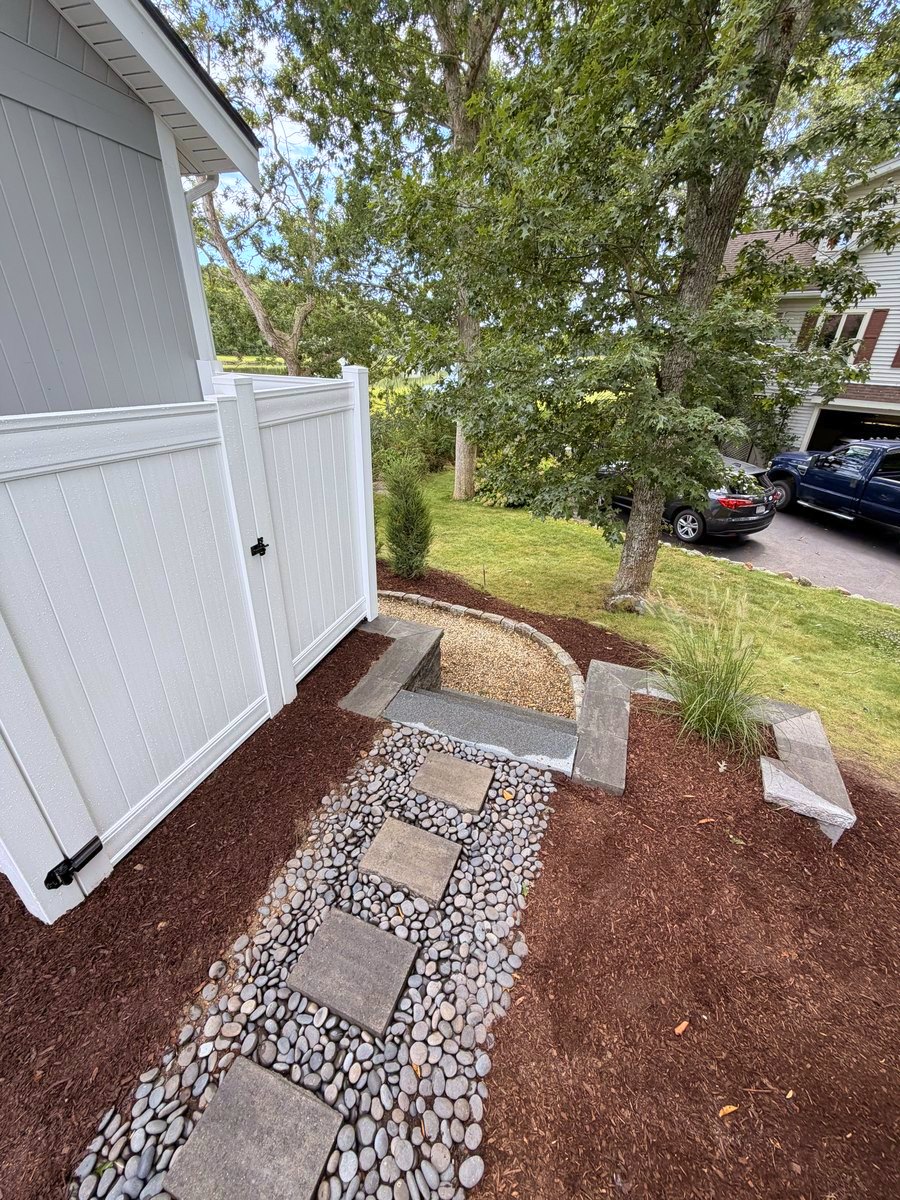 Stepping stones set through black river stone, running past the enclosure to the granite step at the lawn