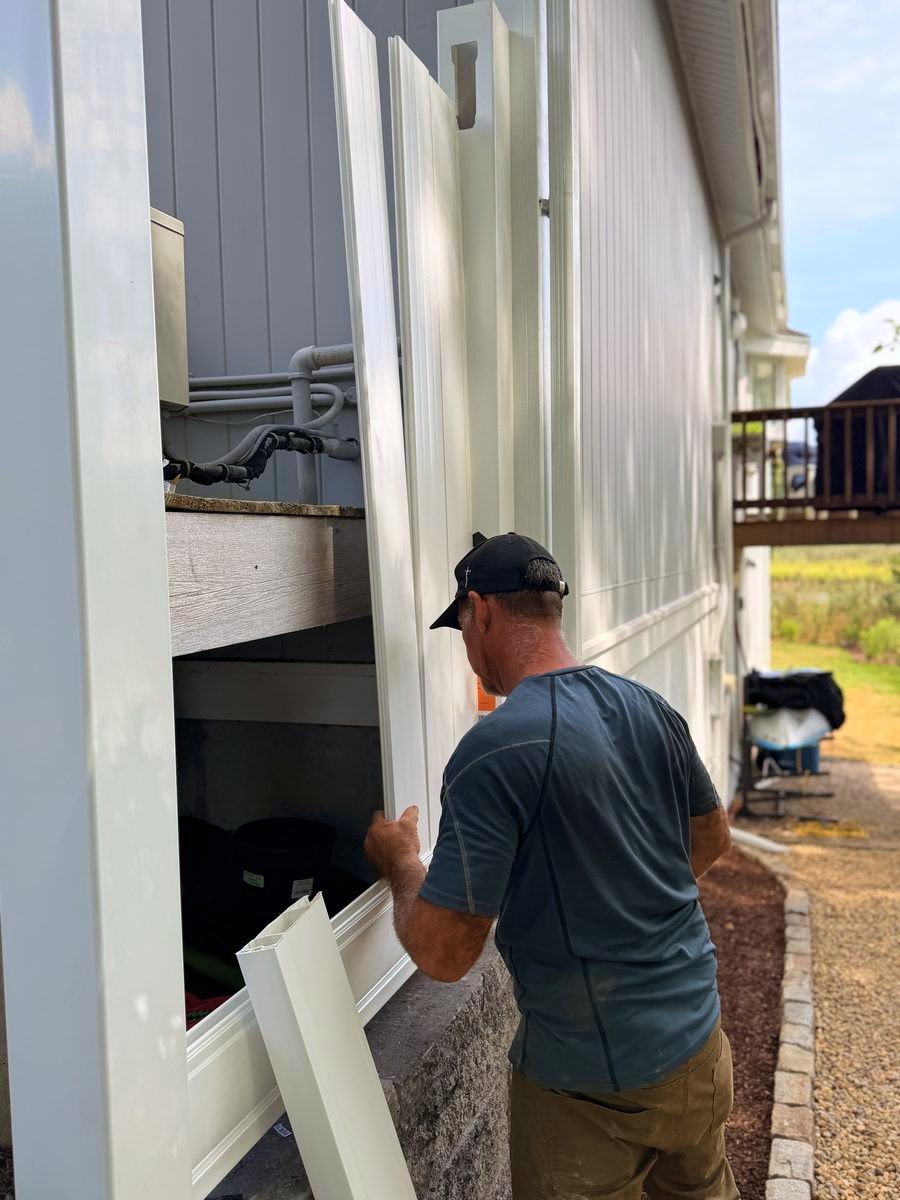 Fitting a vinyl fence panel into the framing under the deck, storage nook behind it