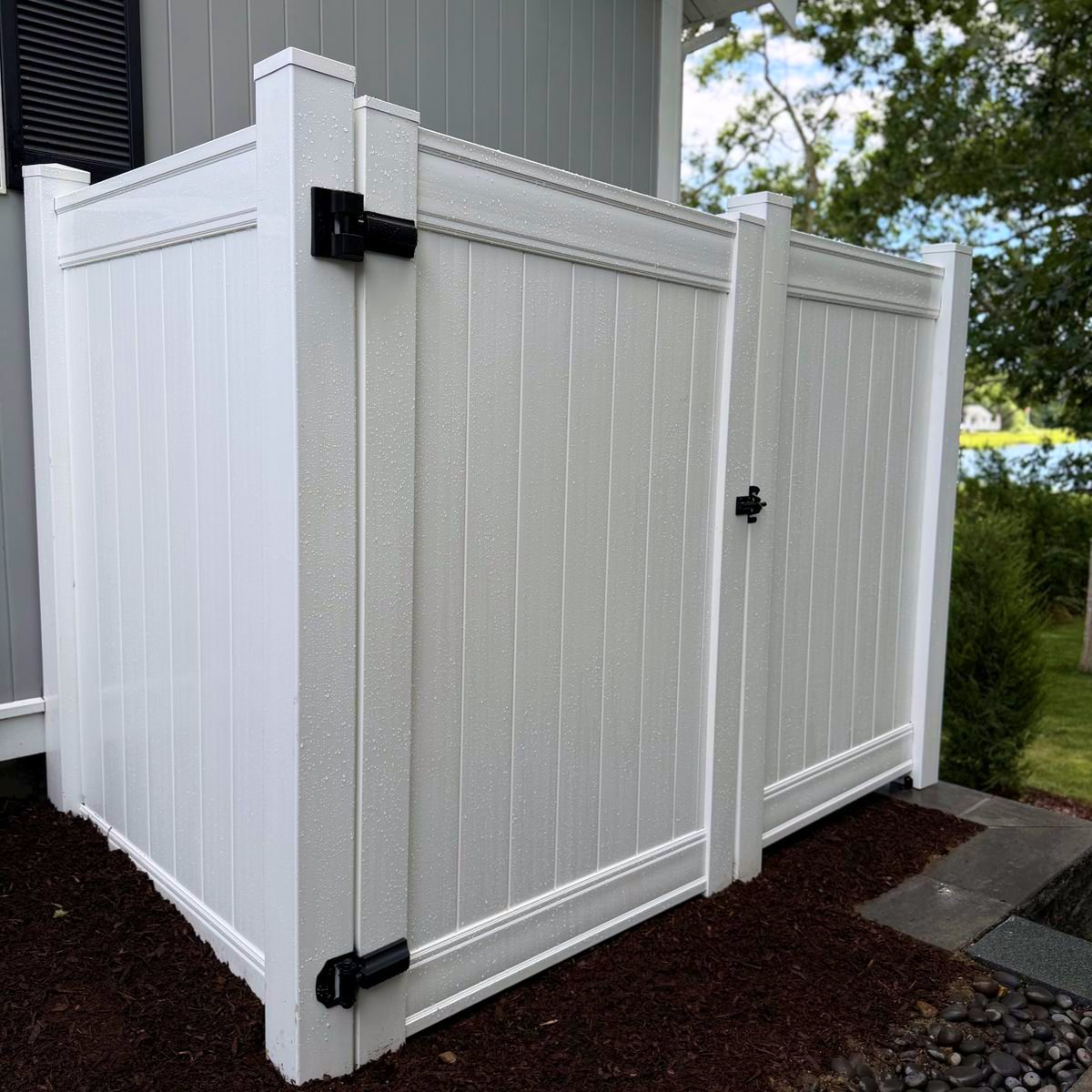 Finished vinyl enclosure with gate hung and latch set, wet from rain