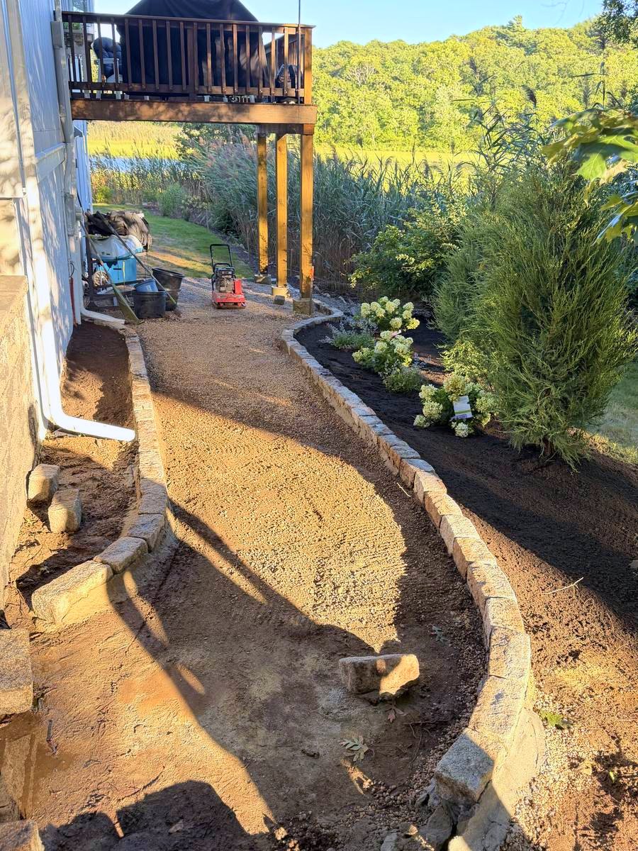 Stone going down between the two cobble edges, first shrubs set in the bed alongside