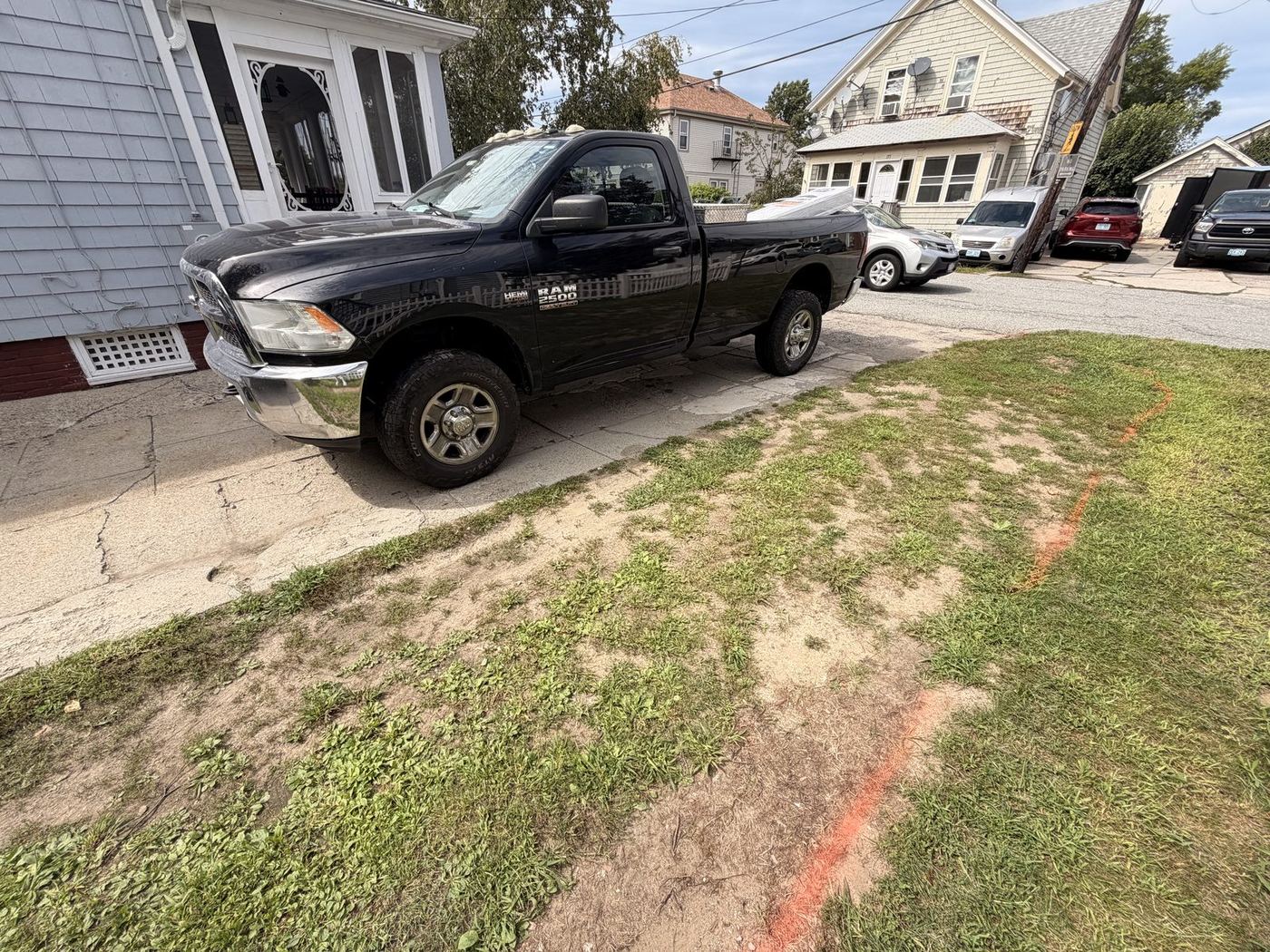 Orange marking paint across the lawn beside the driveway, showing the new edge